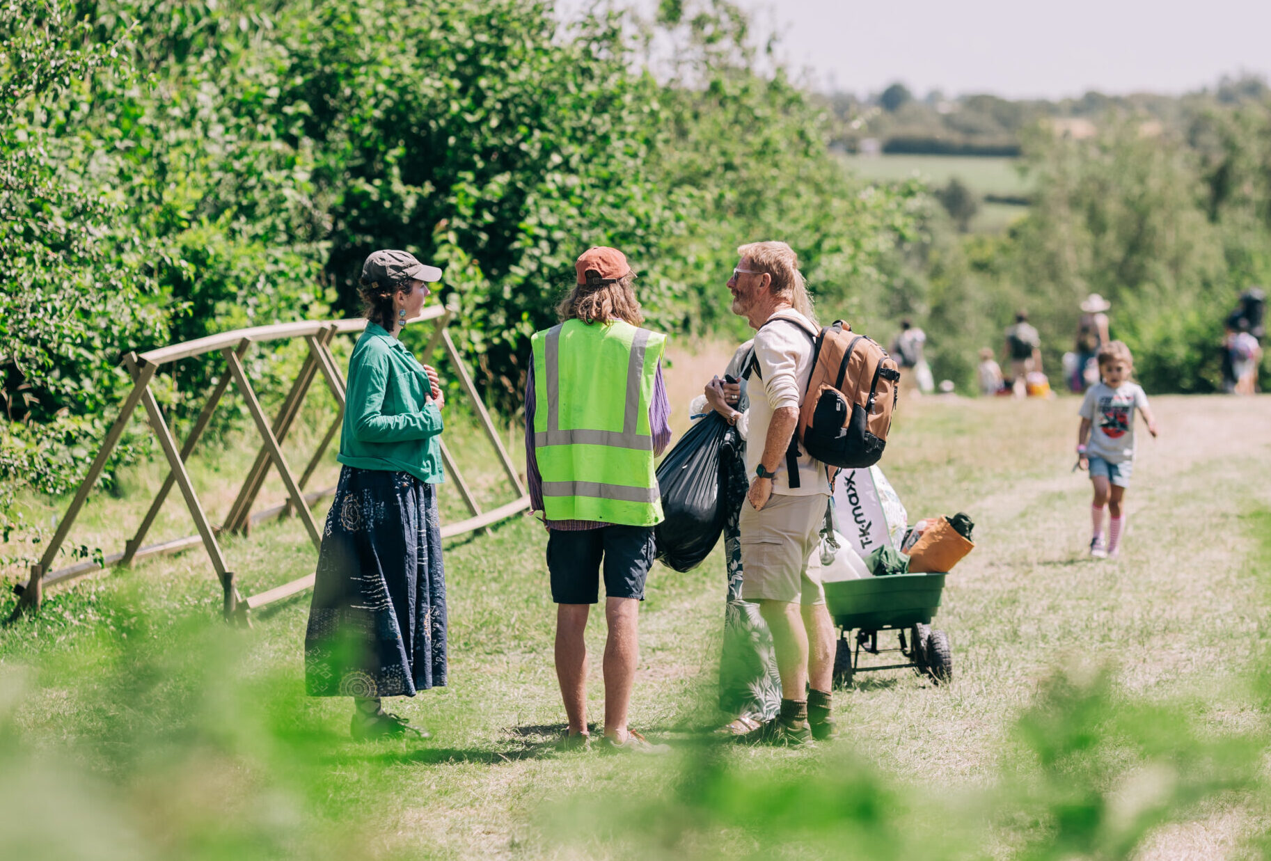 A staff member in a high vis speaks to a family of festival goers as they arrive on site