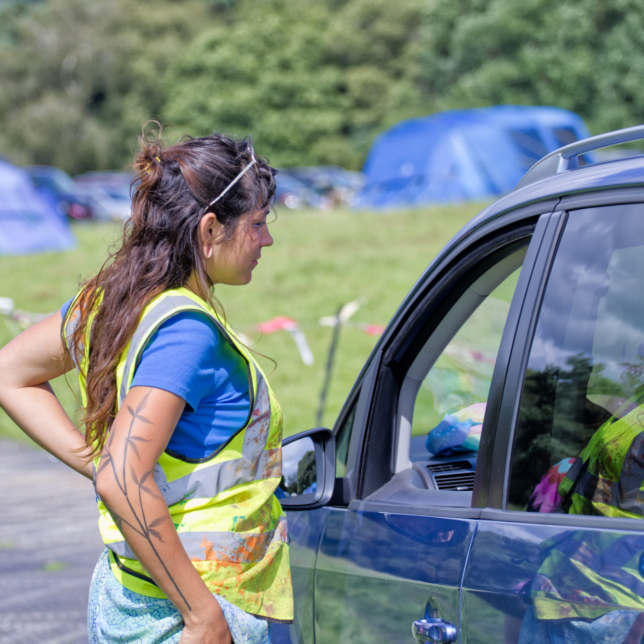 A parking attendant in a high vis vest helps a driver park their car at Just So Festival.